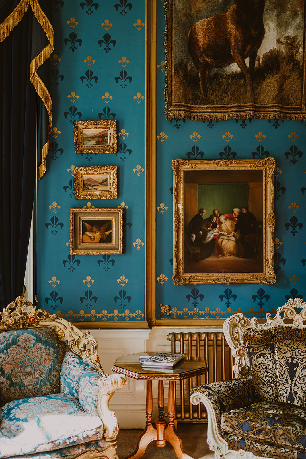 Blue sitting room inside Drumtochty Castle decorated with paintings and antique furniture