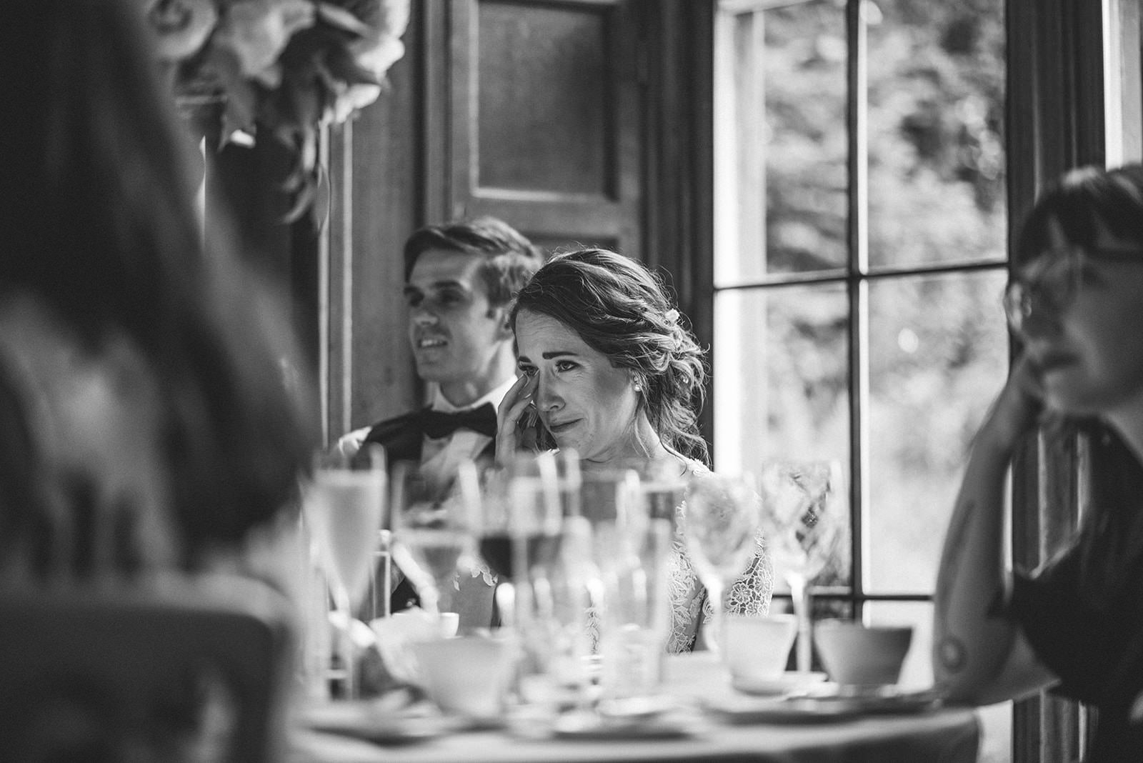 Black and white photograph of the newlyweds listening to speeches at their reception