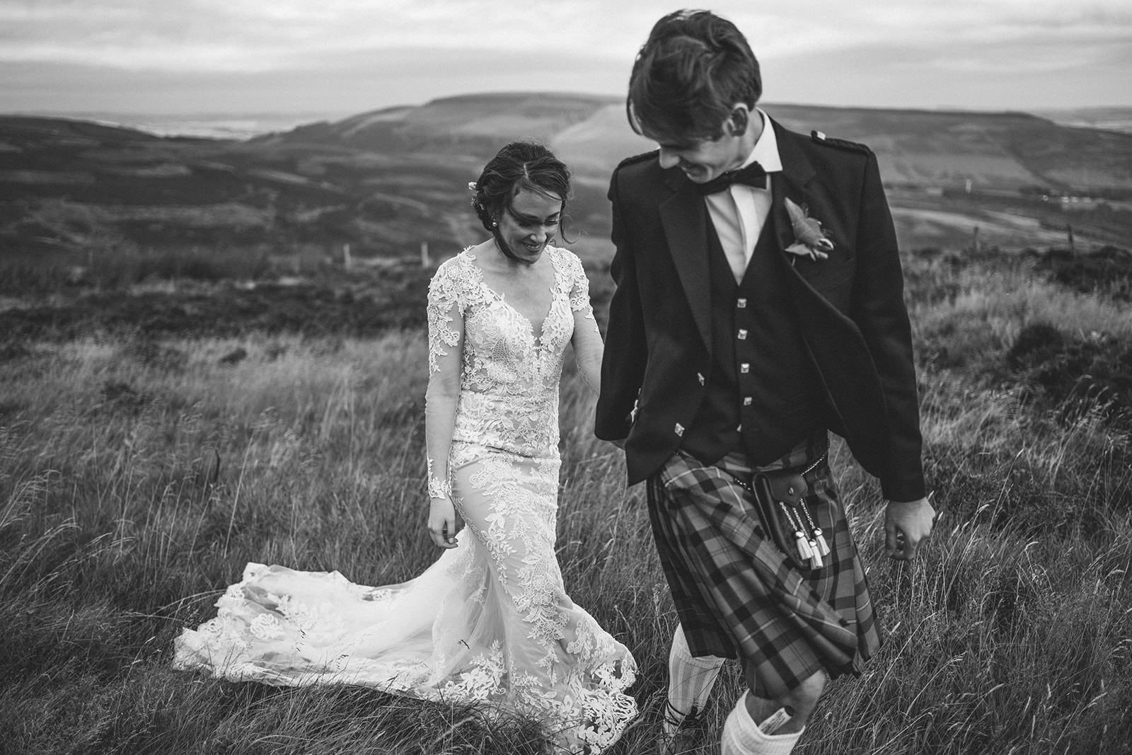 Black and white photograph of the newlyweds walking through Scottish moorland